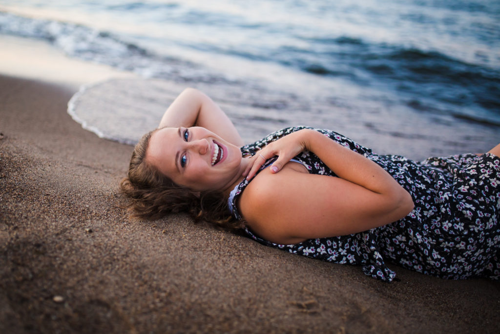 Girl laying on the beach getting hit by waves