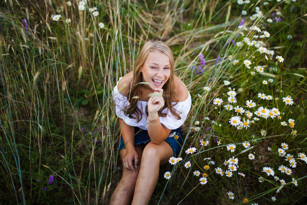 Girls sitting in field of flowers winking