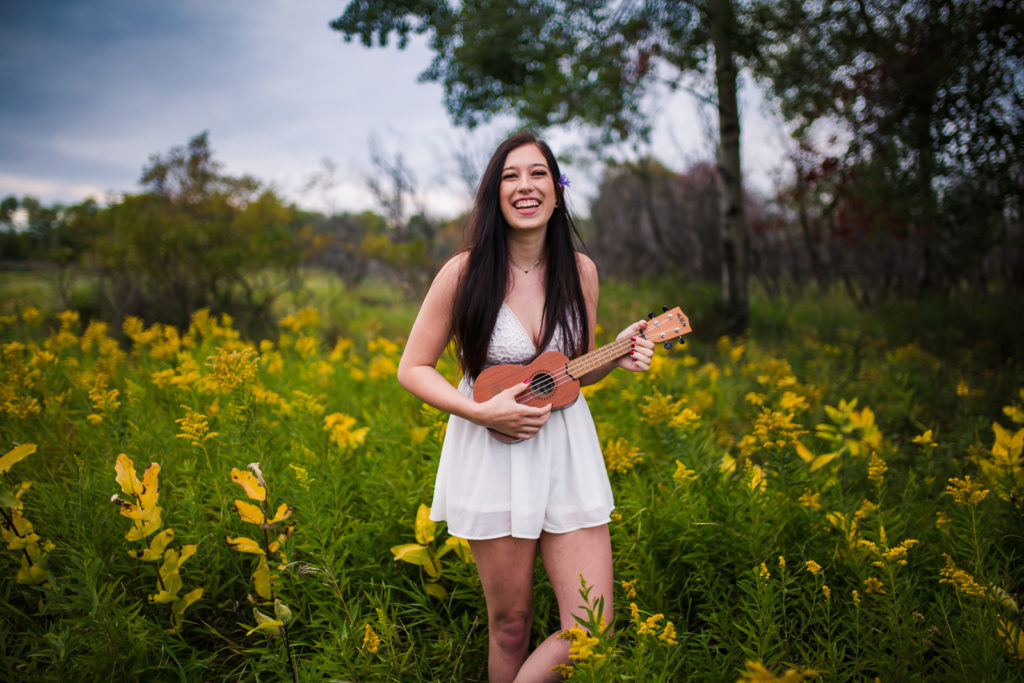 Girl playing ukulele in a field of wildflowers